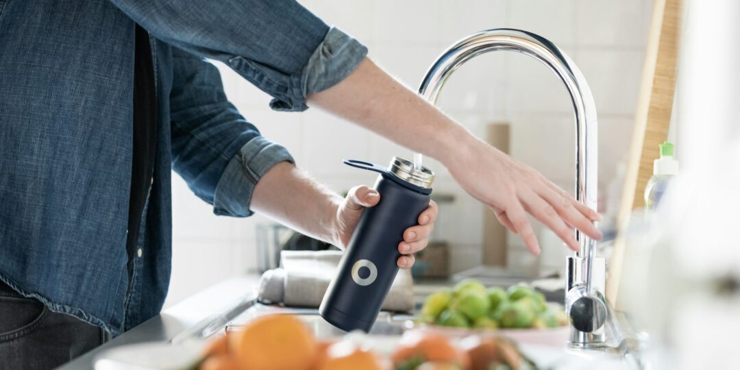 person in blue denim jacket holding stainless steel bottle