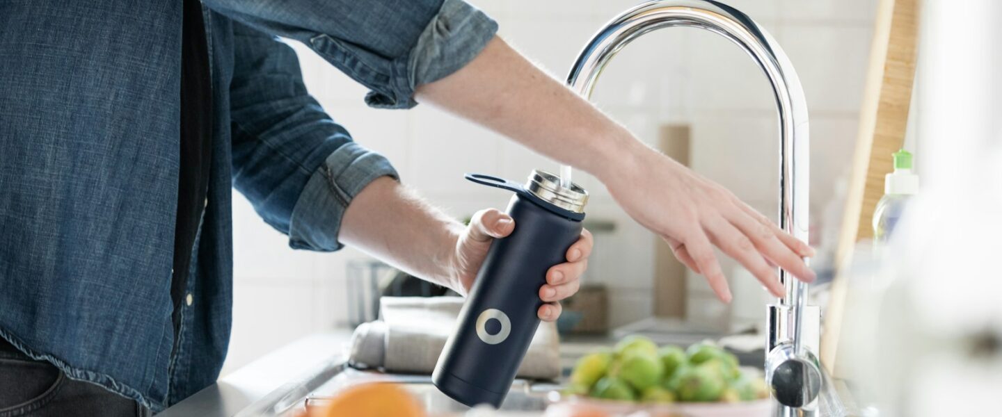 person in blue denim jacket holding stainless steel bottle